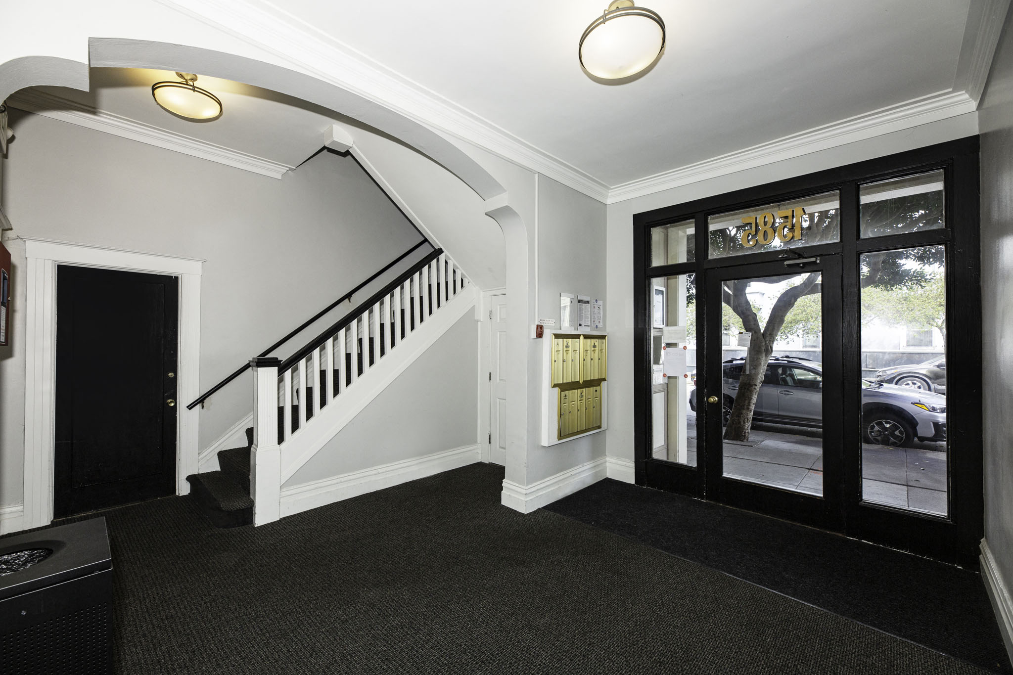 A black and white hallway with a staircase and a glass door.