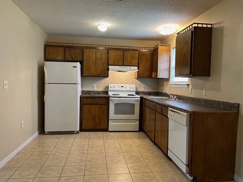 A kitchen with white appliances and brown cabinets.