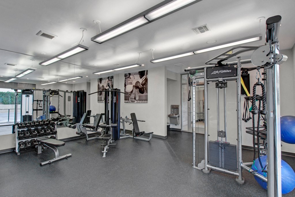 a gym with weights and cardio equipment in a building with white walls