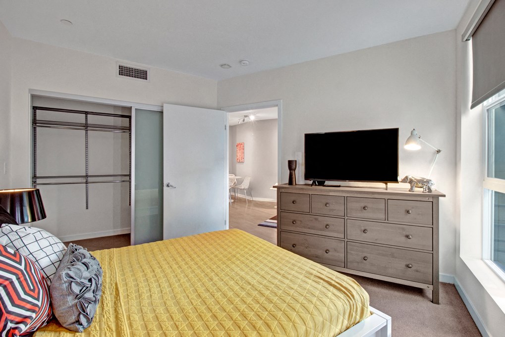a bedroom with a yellow bed and a tv on top of a dresser