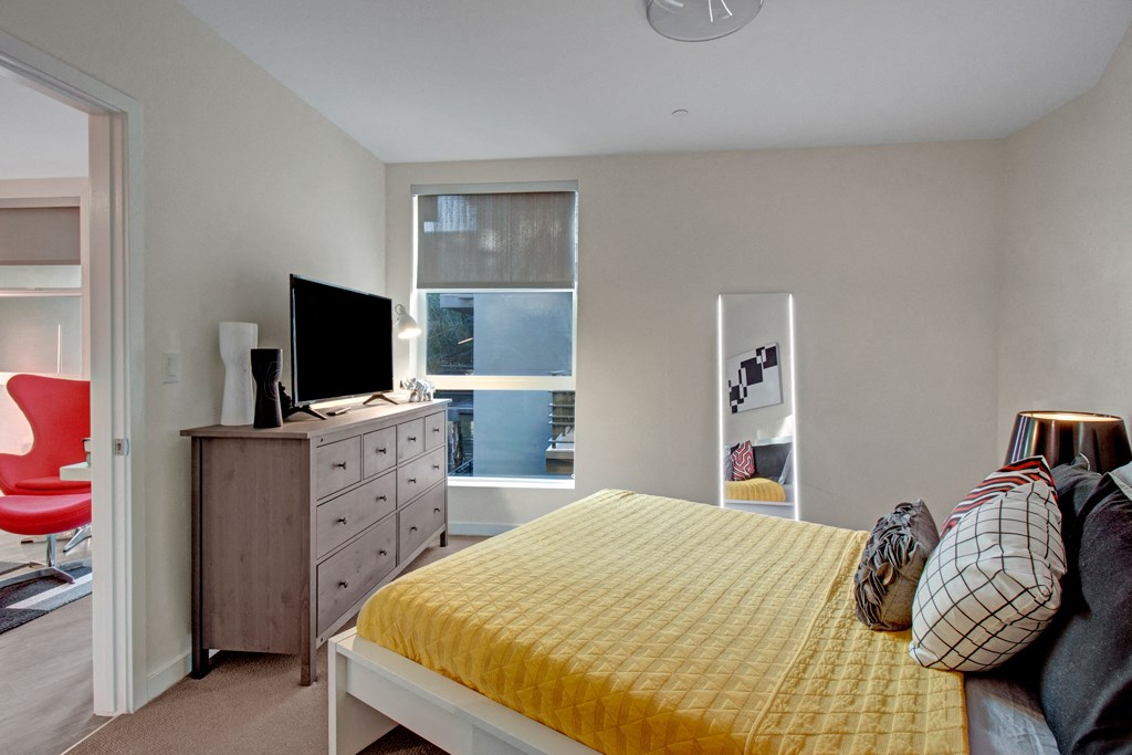 a bedroom with a bed and a dresser with a tv