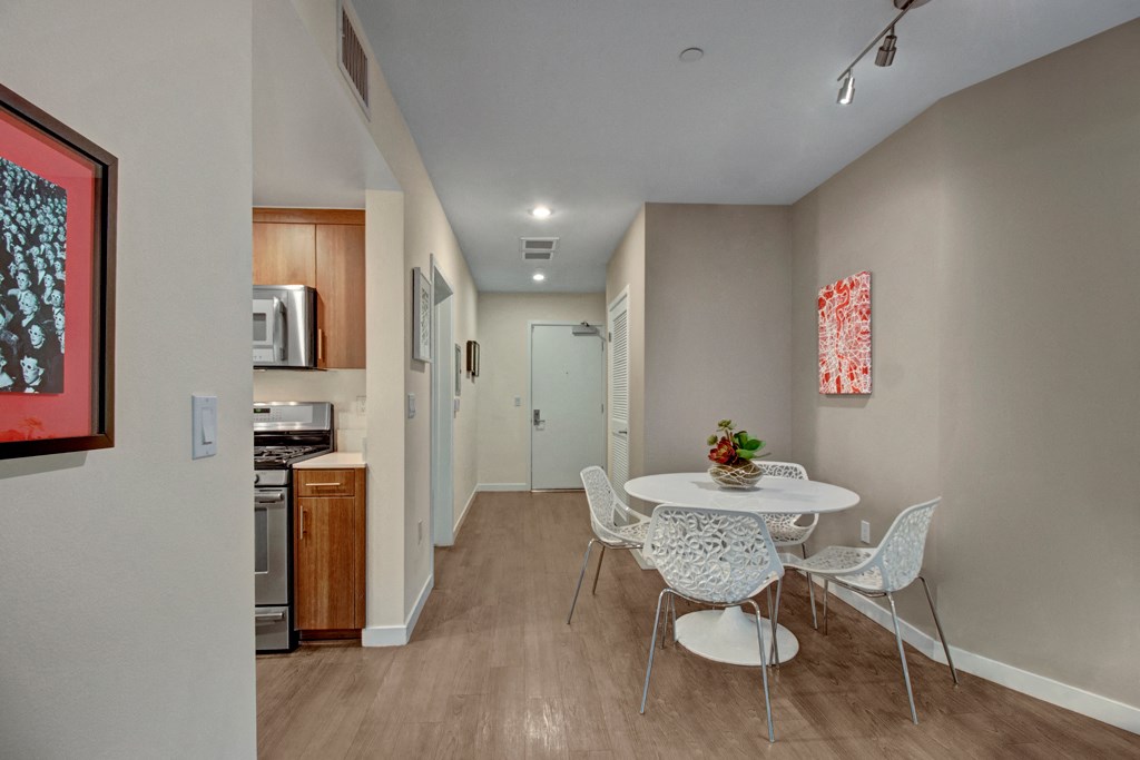a dining room with a table and chairs and a kitchen with a microwave