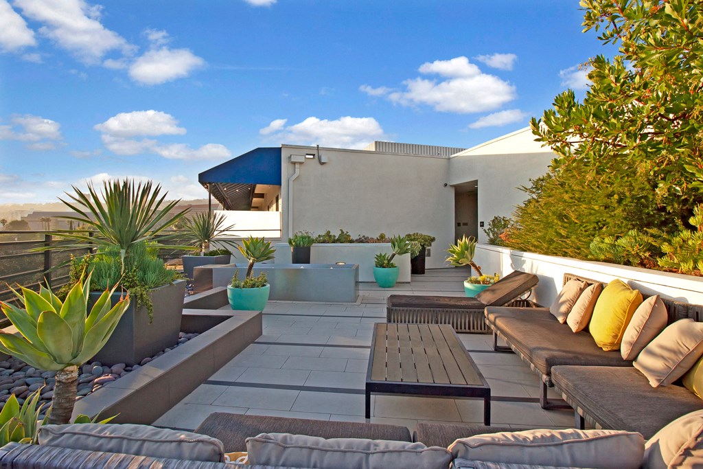 a rooftop patio with couches and tables and plants