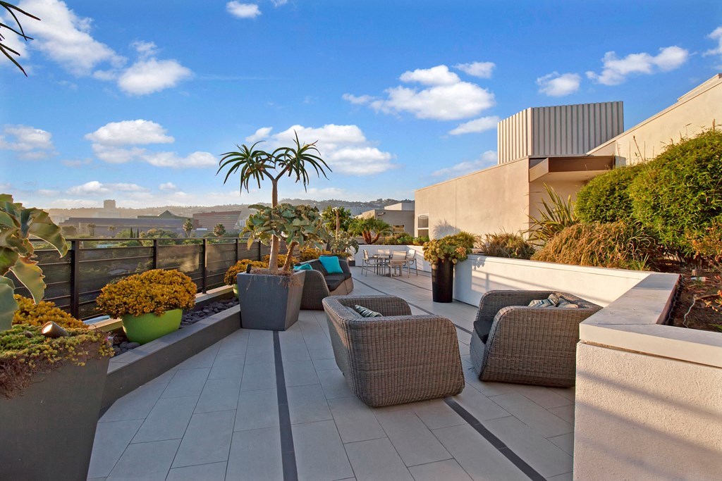 a roof terrace with wicker furniture and potted plants
