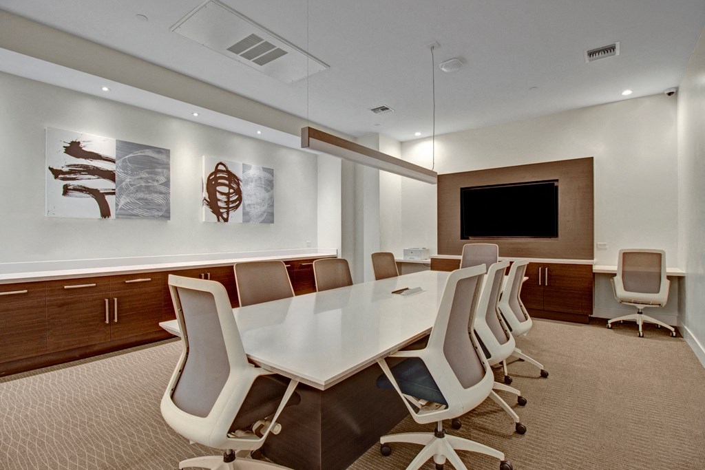 a conference room with a white table and chairs and a television