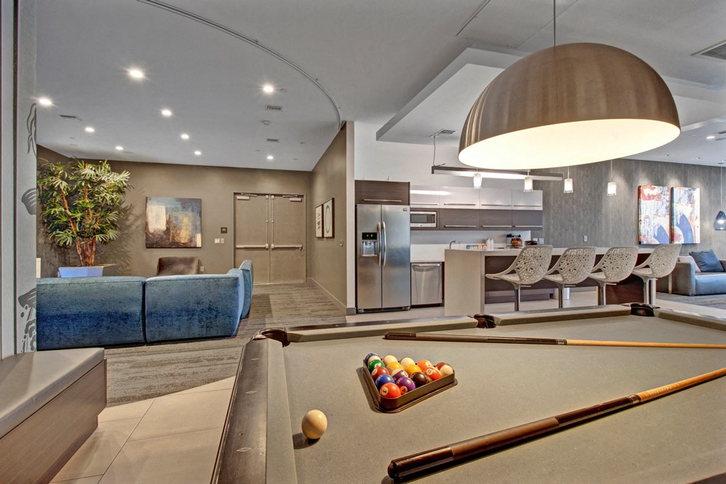 a game room with a pool table and a kitchen