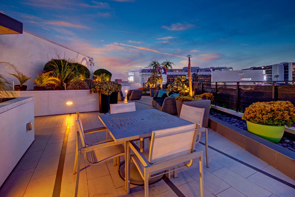 a rooftop terrace with a table and chairs and a city at dusk