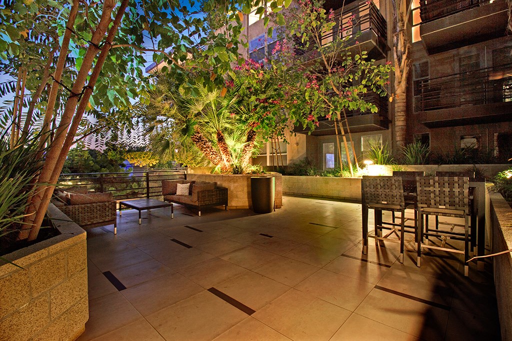 a patio at night with tables and chairs and trees