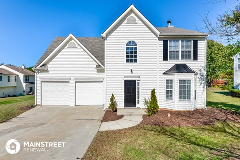 a white house with a black door and a driveway