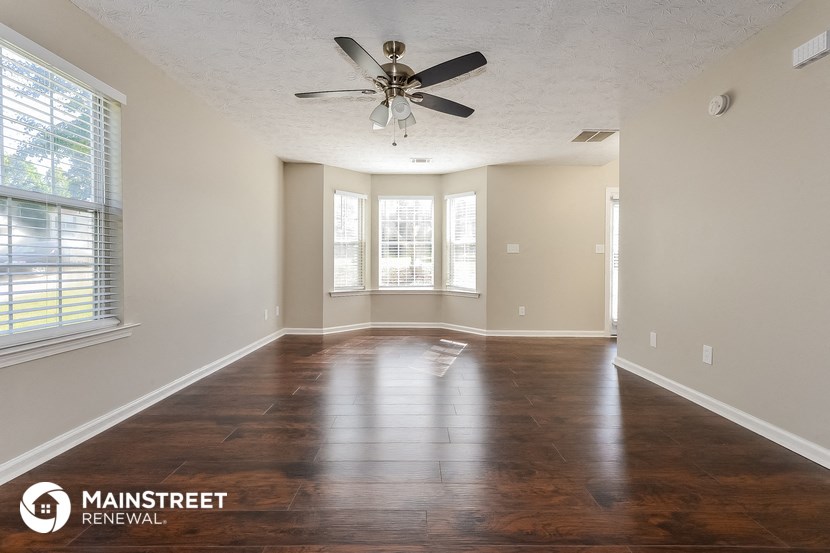 an empty living room with wood floors and a ceiling fan