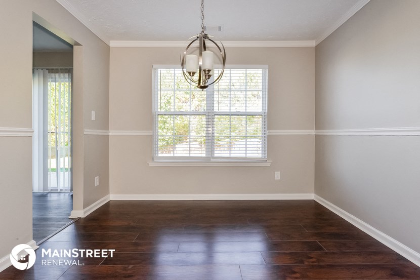 an empty living room with a large window and wooden floors