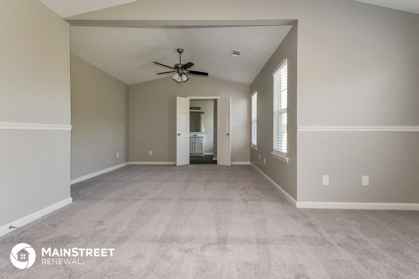 a large empty living room with a ceiling fan