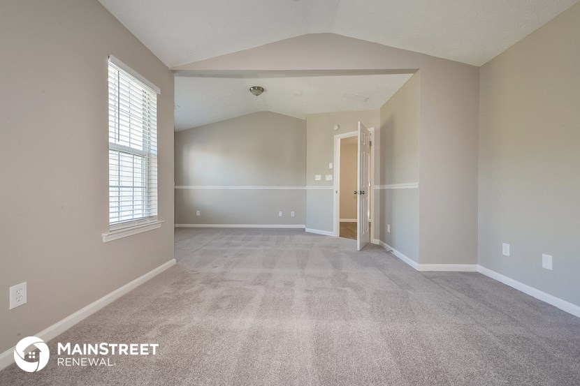 the spacious living room with carpeted flooring and window