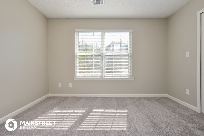 an empty room with a window and a carpeted floor