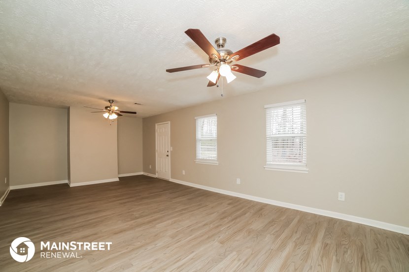 the spacious living room with ceiling fan and wood flooring