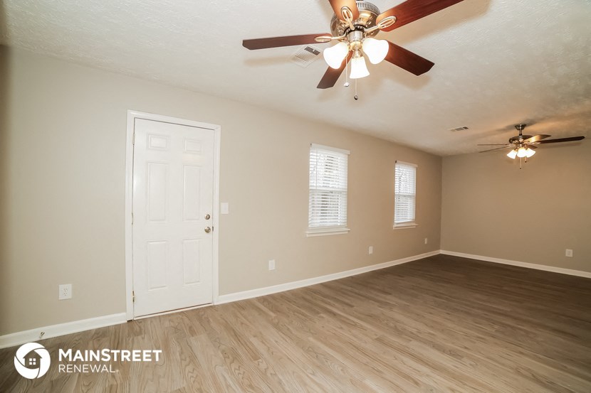 the living room of an empty house with a ceiling fan