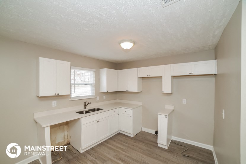 a kitchen with white cabinets and a sink and a window