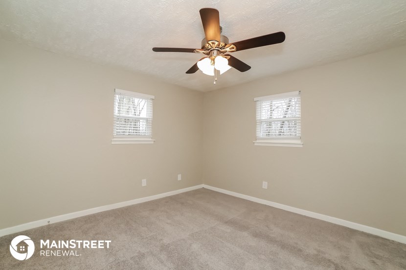 the bedroom has a ceiling fan and a carpeted floor