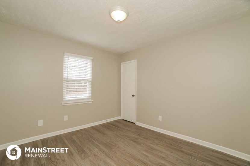 the spacious living room with hardwood flooring and white walls