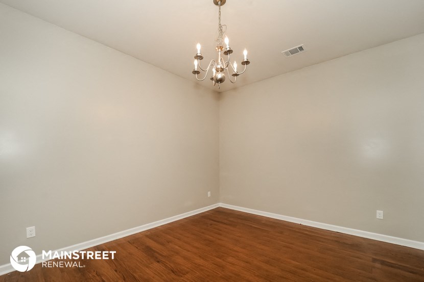 a bedroom with a wood floor and white walls and a chandelier