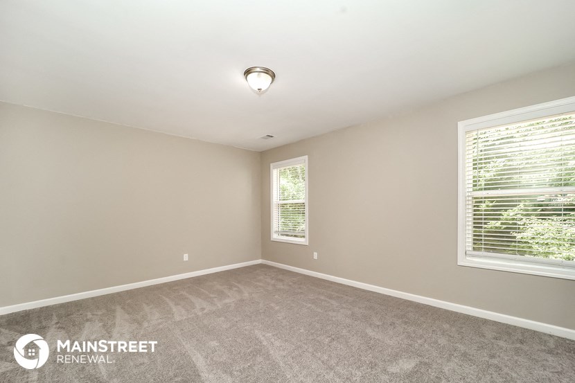 the spacious living room with carpeted flooring and large windows