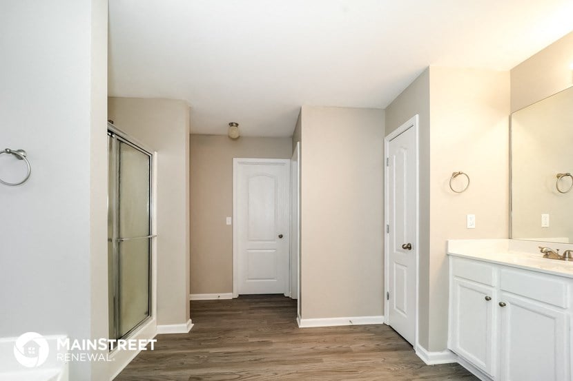 a bathroom with white cabinets and a sink and a mirrored closet