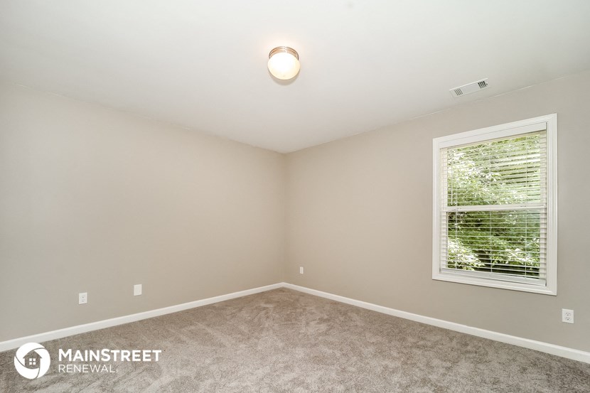 the master bedroom has a large window and carpeted flooring