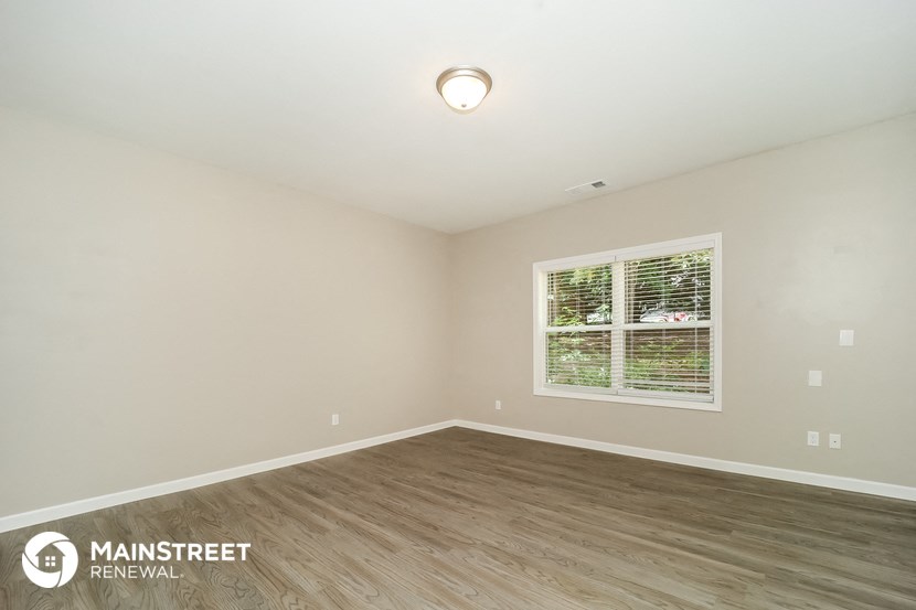 the spacious living room with wood flooring and a large window