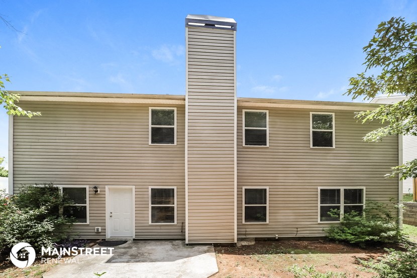 the front of a tan house with a white door
