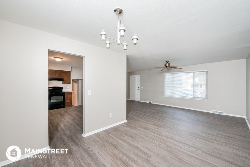 the living room and dining room with wood flooring and a ceiling fan