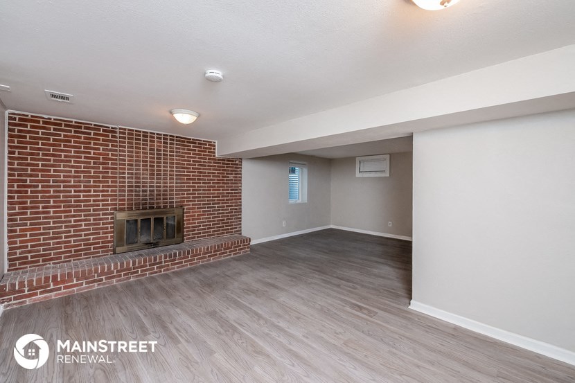 the living room of an apartment with a brick fireplace