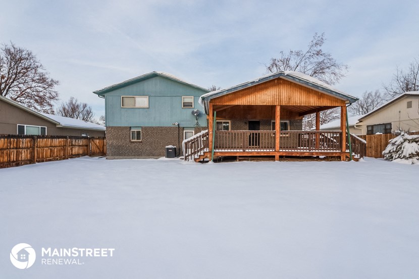 a covered porch with a blue house in the snow