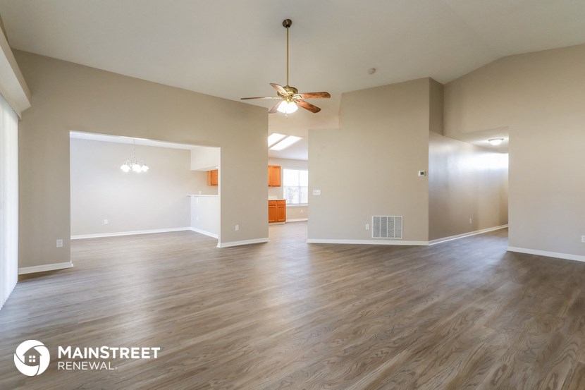 the living room and dining room with wood flooring and ceiling fan