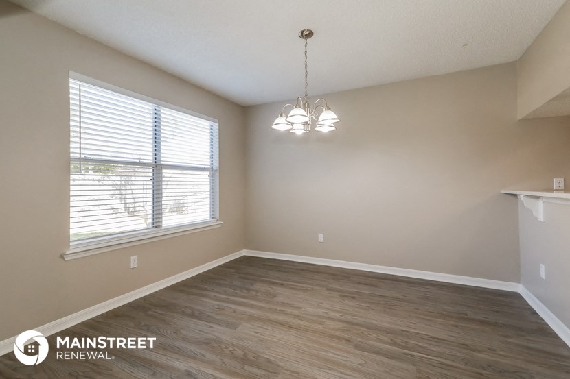 the spacious living room of an apartment with wood flooring and a large window