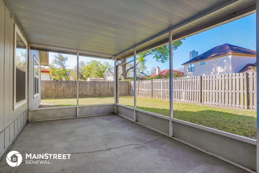 a patio with a white fence and a backyard with grass