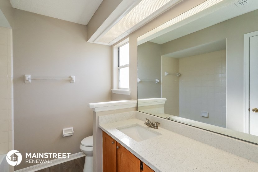 a bathroom with a large mirror and a sink and a toilet