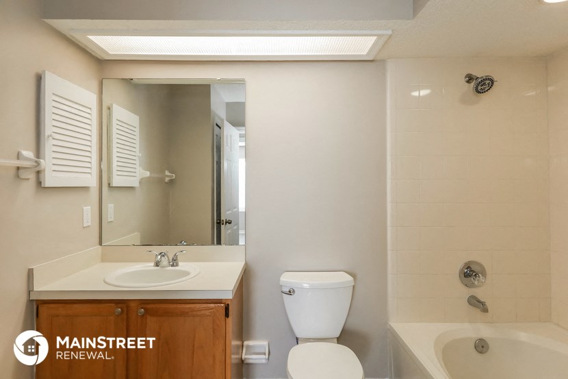 a bathroom with a toilet sink and mirror and a tub