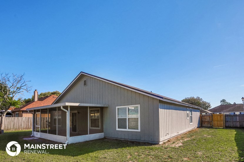 a small gray house with a yard and a fence