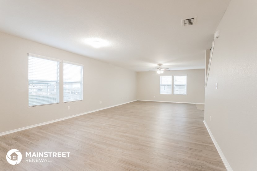 the spacious living room with wood flooring and white walls