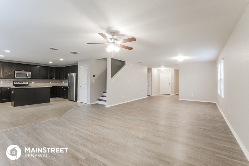 an open living room and kitchen with a ceiling fan