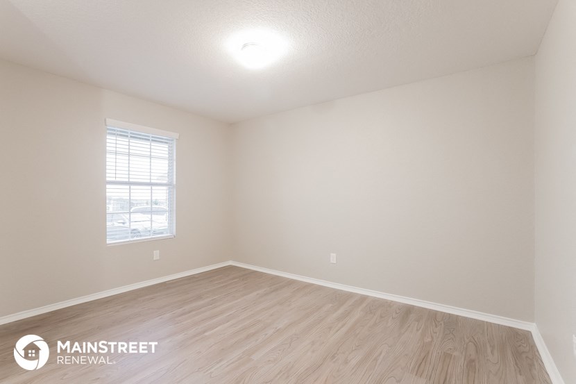 the spacious living room with wood flooring and a window