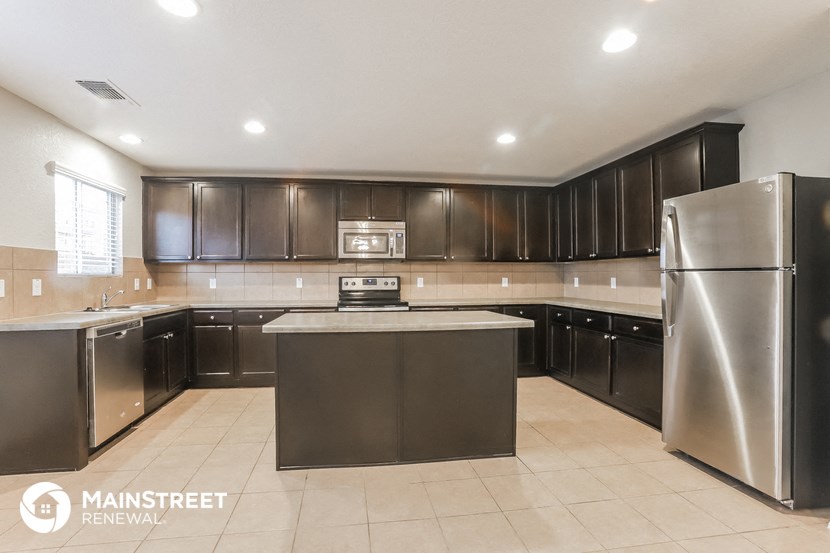 a large kitchen with stainless steel appliances and black cabinets