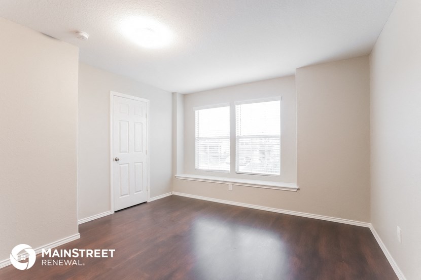 the living room of an apartment with wood flooring and a window