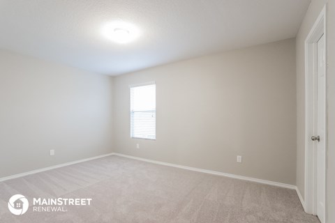 the spacious living room with white carpet and a window