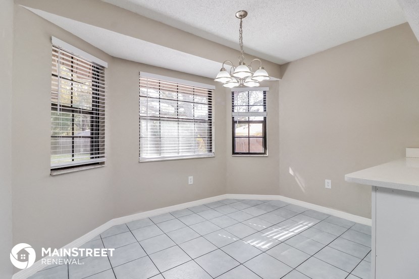 an empty living room with a white tile floor and windows