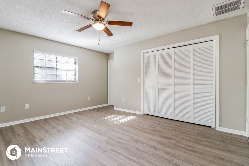 an empty living room with a ceiling fan and a closet