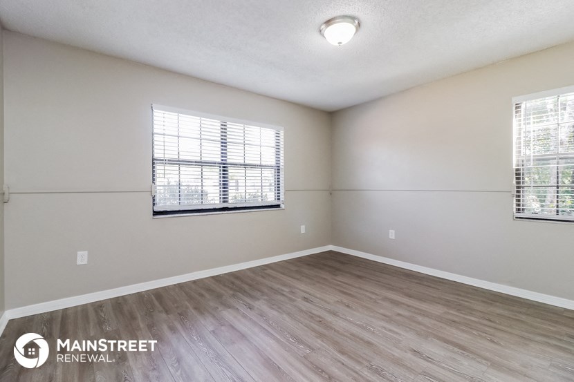 an empty living room with wood flooring and a window