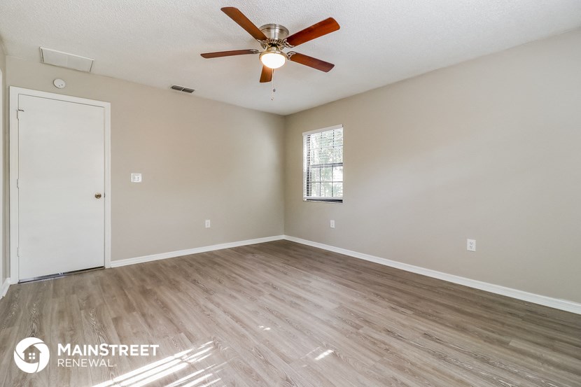 an empty living room with wood flooring and a ceiling fan