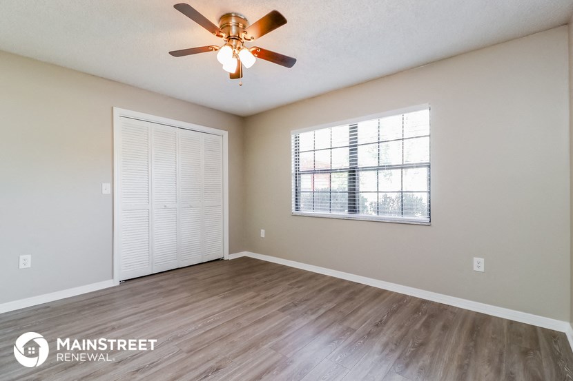 an empty living room with a ceiling fan and a window