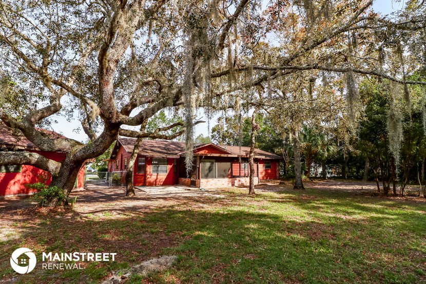 a small red house sitting in a field with trees